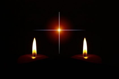 Dwie świece i krzyż na ciemnym tle