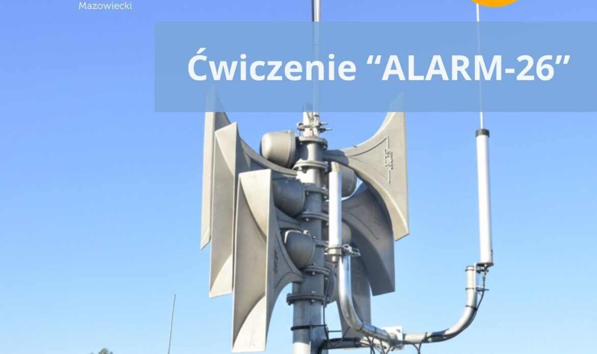 Na zdjęciu widać syrenę alarmową zamontowaną na maszcie na dachu budynku, na tle bezchmurnego nieba. Na środku grafiki umieszczono napis „Ćwiczenie ALARM-26”, a w lewym górnym rogu znajduje się logo Grodziska Mazowieckiego.